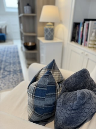 A comfortable white armchair with blue and white cushions in a peacefully lit therapy room.